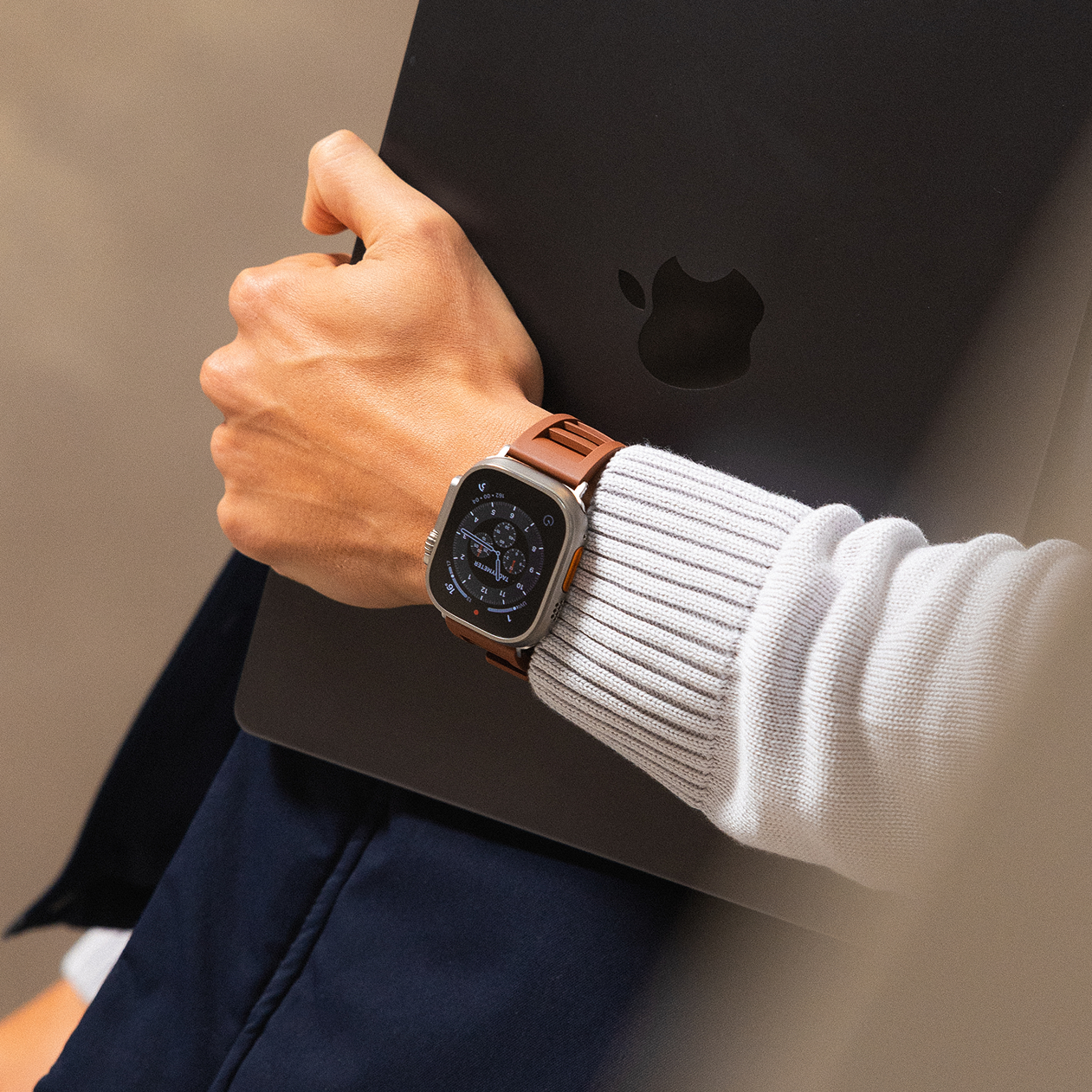 Person holding a black macbook with an Apple logo, wearing an apple watch.