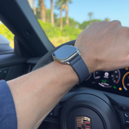 Man wearing The Dorchester Navy Leather Apple Watch Strap driving a Porsche among palm trees