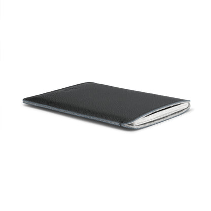 Black leather passport sleeve holding a British passport, angled view – The Bridge