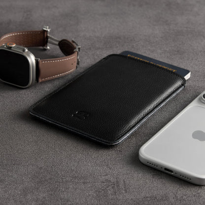 Black leather passport sleeve with Apple Watch and iPhone, angled view – The Bridge
