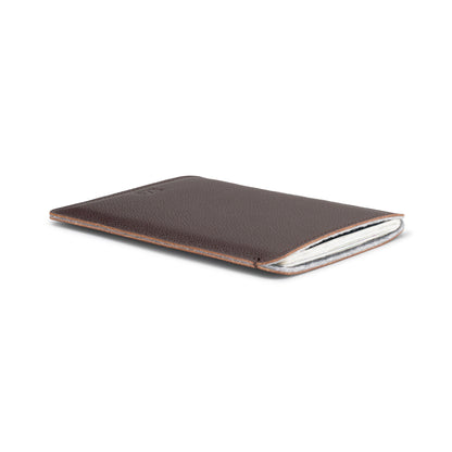 Brown leather passport sleeve holding a British passport, angled view – The Bridge