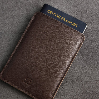 Brown leather passport sleeve with British passport partially inserted, angled view – The Bridge