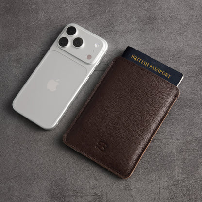 Brown leather passport sleeve and British passport beside silver iPhone – The Bridge
