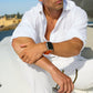 Man in a white shirt sitting on a boat with a watch on his wrist.